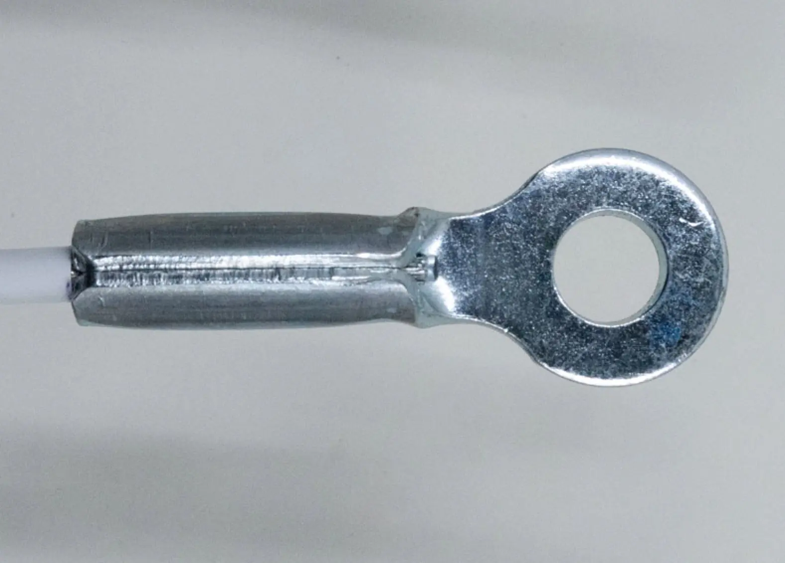 Stamped eye end fitting on grey background, side view.