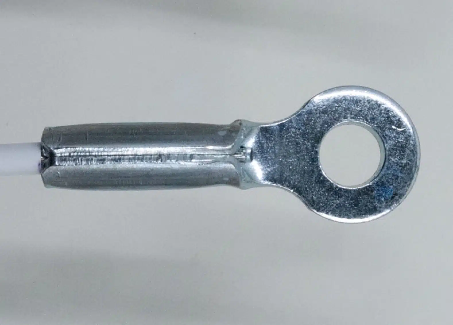 Stamped eye end fitting on grey background, side view.