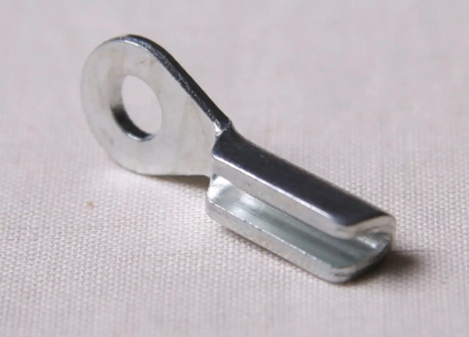 Stamped eye end fitting on grey background, angle view.