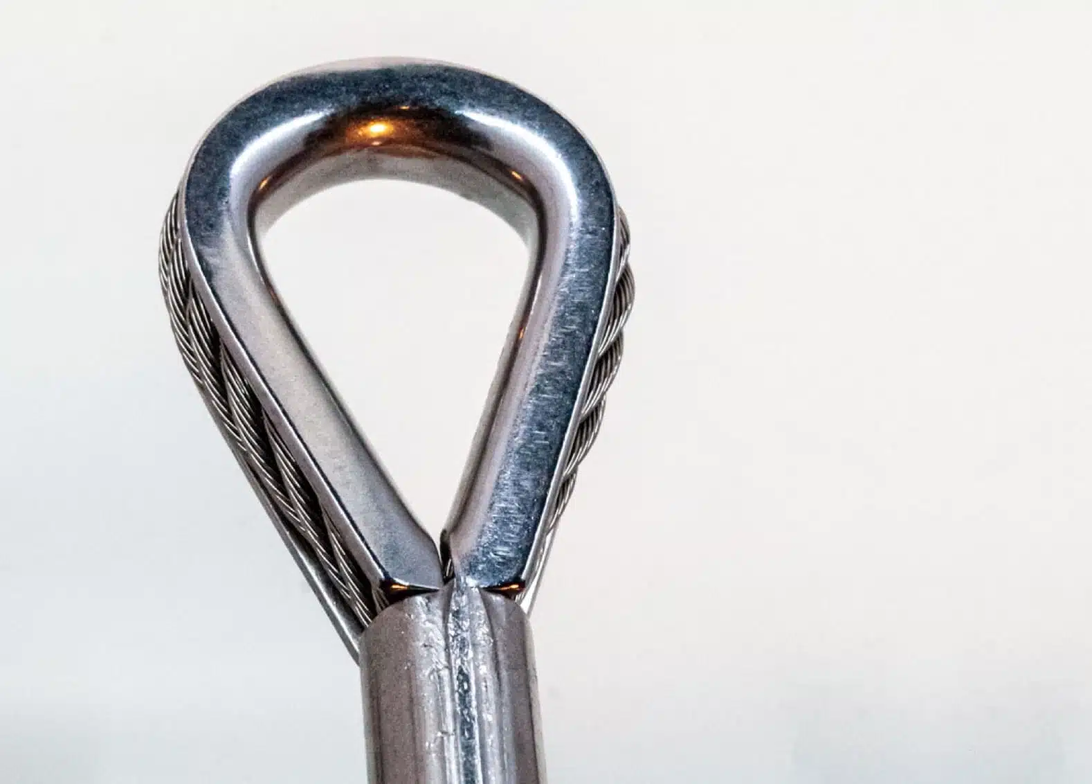 Thimble end fitting with wire rope through it on white background.